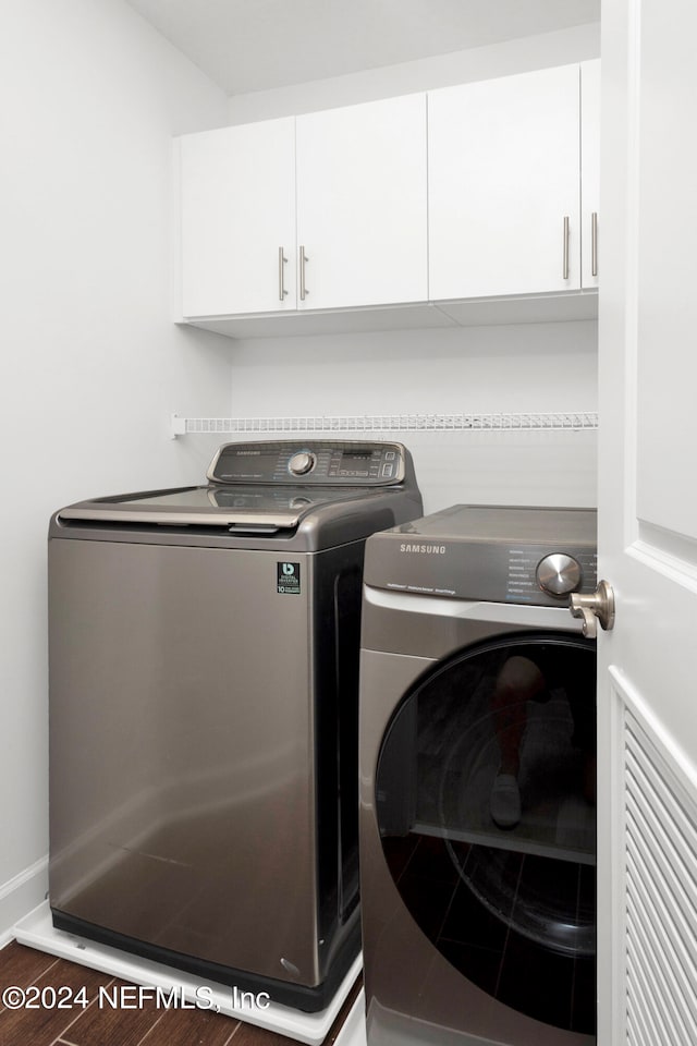 laundry room featuring dark wood-type flooring, cabinets, and washing machine and dryer