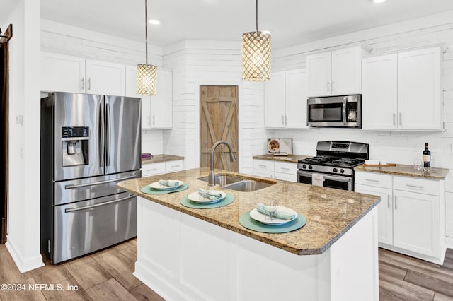 kitchen featuring a sink, stainless steel appliances, decorative backsplash, and light wood finished floors