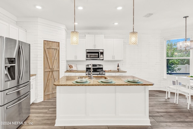 kitchen with decorative light fixtures, stainless steel appliances, light stone countertops, and white cabinets