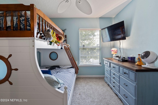 carpeted bedroom featuring ceiling fan and a textured ceiling