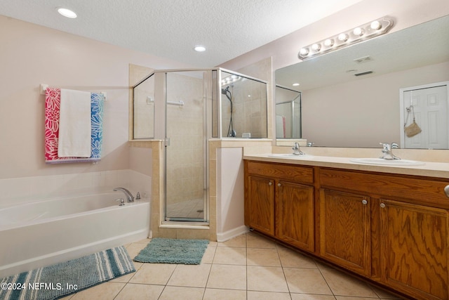 bathroom with a textured ceiling, double vanity, independent shower and bath, and tile patterned floors