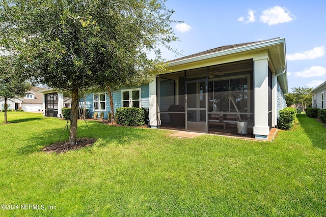 back of property with a sunroom and a lawn