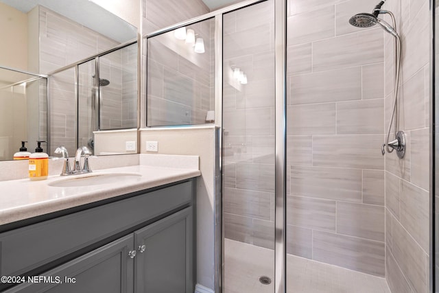 bathroom featuring a shower with door and vanity