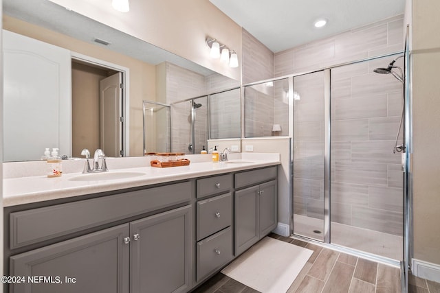 bathroom with a shower with door and dual bowl vanity