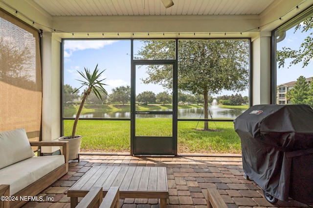 sunroom featuring a water view