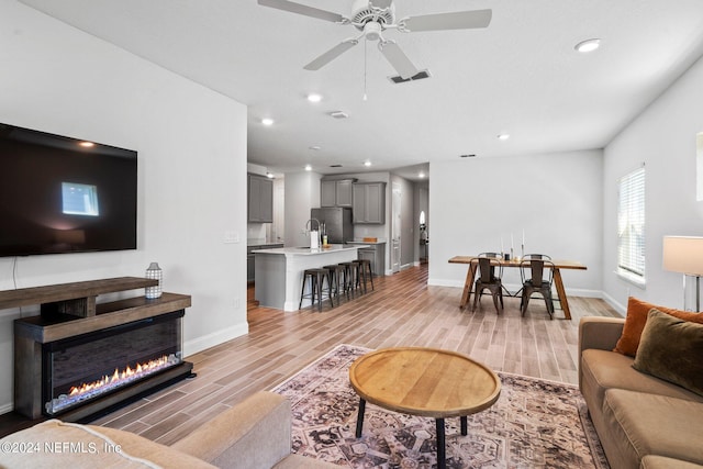 living room featuring ceiling fan, sink, and light hardwood / wood-style floors