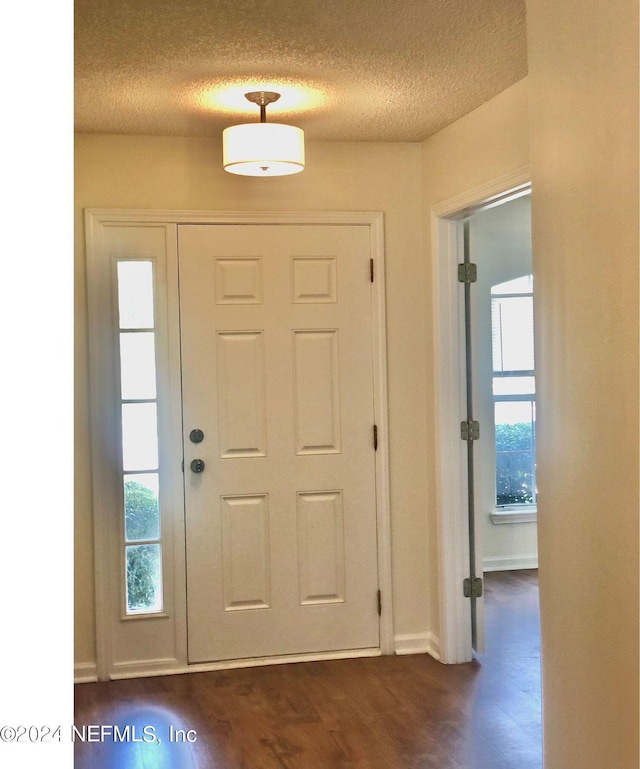 foyer entrance featuring dark hardwood / wood-style flooring and a textured ceiling