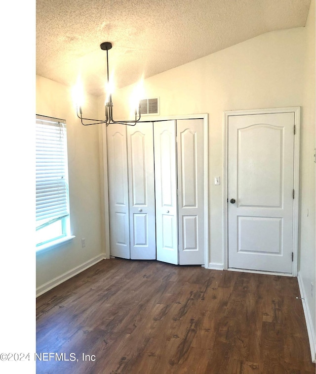 unfurnished bedroom featuring vaulted ceiling, a textured ceiling, a chandelier, and dark hardwood / wood-style floors