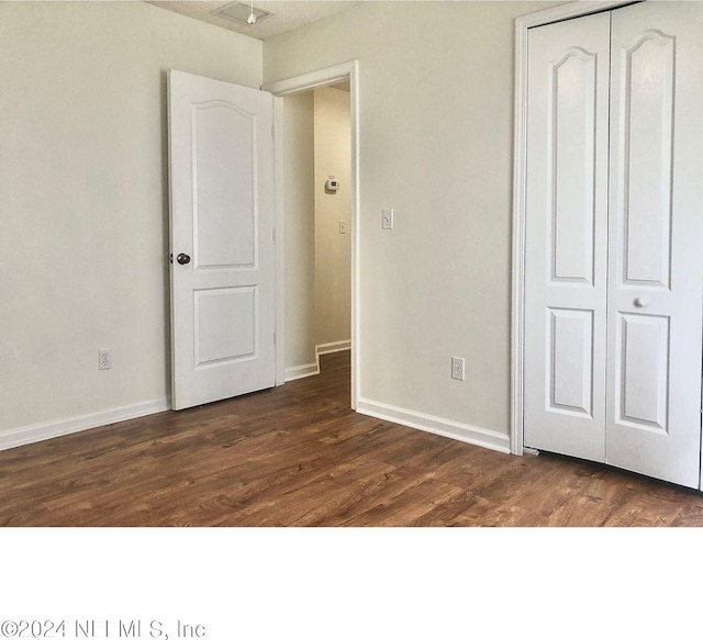 unfurnished bedroom featuring dark wood-type flooring and a closet