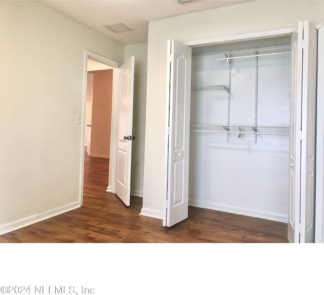 unfurnished bedroom featuring a closet and dark hardwood / wood-style flooring