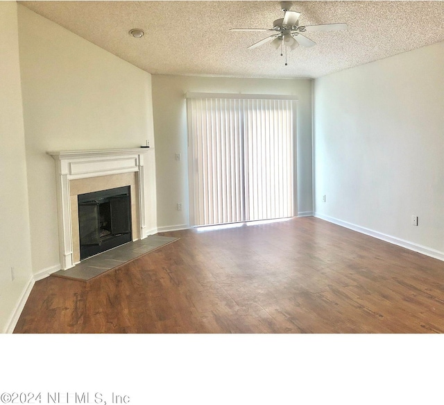 unfurnished living room featuring a textured ceiling, ceiling fan, a tiled fireplace, and dark hardwood / wood-style flooring