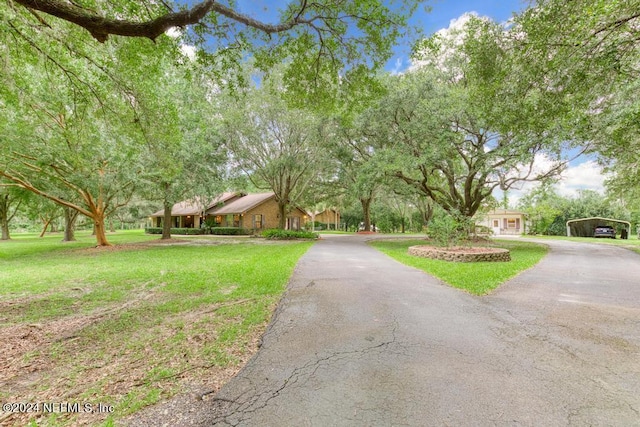 view of front of house with aphalt driveway, a detached carport, and a front lawn