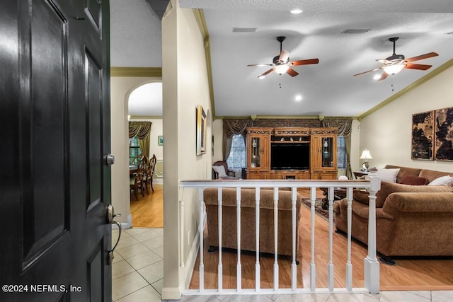 living room featuring arched walkways, ornamental molding, vaulted ceiling, and ceiling fan