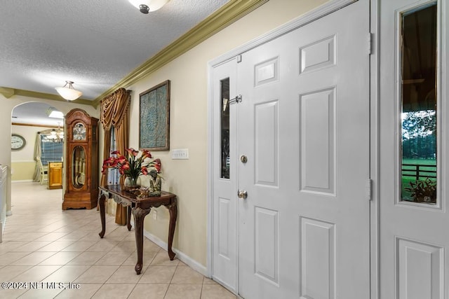 foyer entrance with crown molding, a textured ceiling, and light tile patterned floors