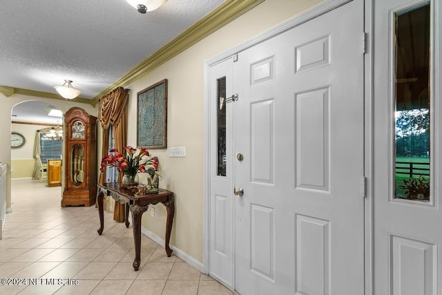 corridor featuring light tile patterned flooring, a textured ceiling, baseboards, ornamental molding, and arched walkways