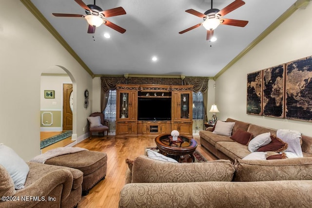 living room with lofted ceiling, hardwood / wood-style floors, ornamental molding, arched walkways, and a ceiling fan