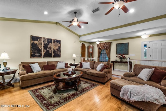 living room with crown molding, light wood-type flooring, lofted ceiling, ceiling fan, and a textured ceiling