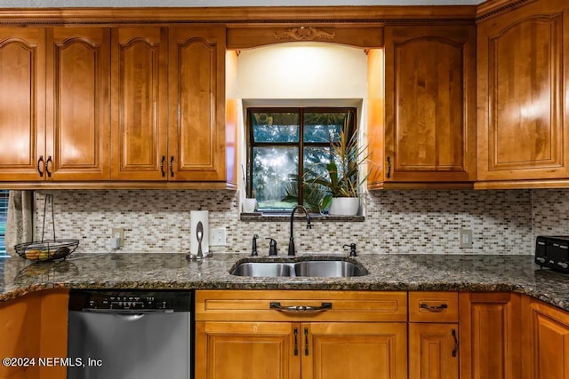 kitchen featuring backsplash, a sink, stainless steel dishwasher, brown cabinets, and dark stone counters
