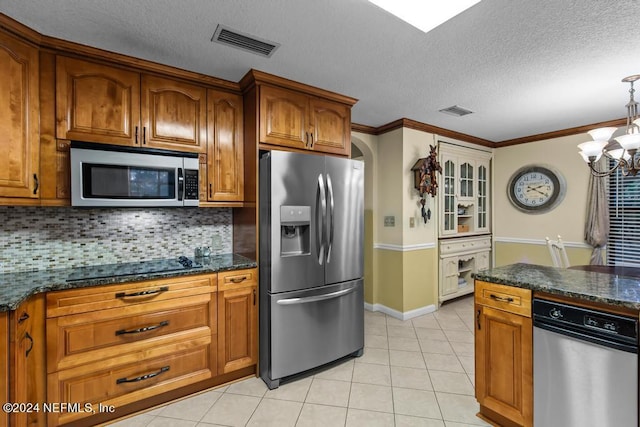 kitchen with light tile patterned floors, appliances with stainless steel finishes, a chandelier, and decorative backsplash