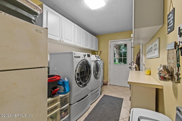 clothes washing area featuring cabinets, light tile patterned floors, washer and clothes dryer, and a textured ceiling