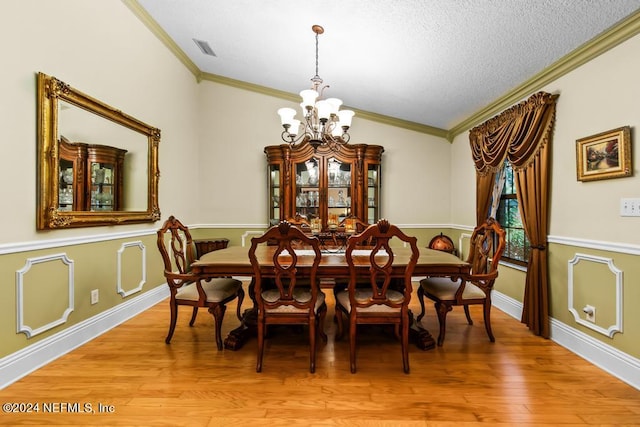 dining area with ornamental molding, vaulted ceiling, a notable chandelier, and light hardwood / wood-style floors