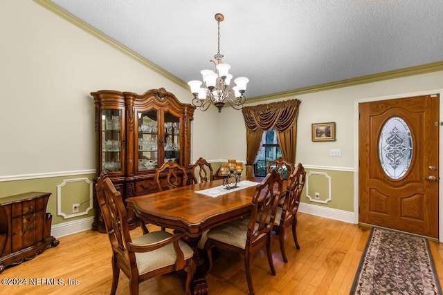 dining area with a textured ceiling, a chandelier, crown molding, and light wood finished floors