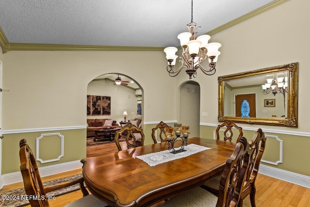 dining room featuring a textured ceiling, ceiling fan with notable chandelier, light hardwood / wood-style flooring, ornamental molding, and lofted ceiling