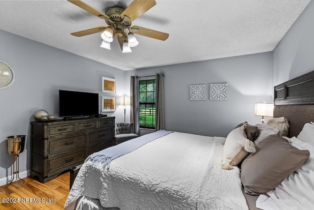 bedroom featuring baseboards, a ceiling fan, light wood-style flooring, and a textured ceiling