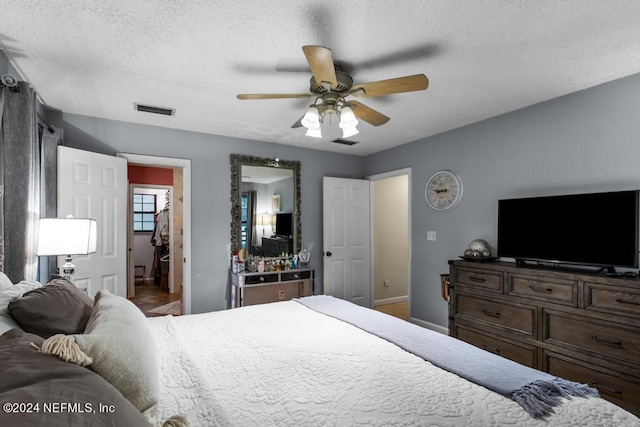 bedroom with a textured ceiling, ceiling fan, and wood-type flooring