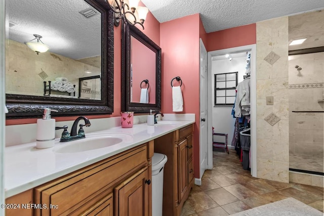 bathroom with tile patterned floors, tiled shower, a textured ceiling, and vanity