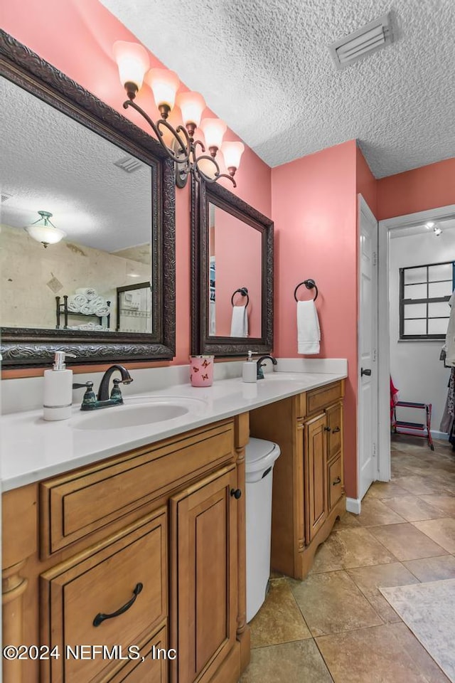 bathroom with tile patterned floors, a chandelier, a textured ceiling, and vanity