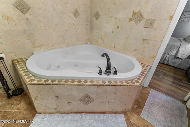 ensuite bathroom featuring tile patterned floors, a whirlpool tub, connected bathroom, and tile walls