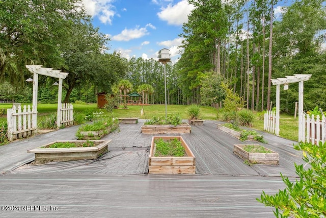 wooden deck featuring a lawn, a pergola, fence, and a vegetable garden