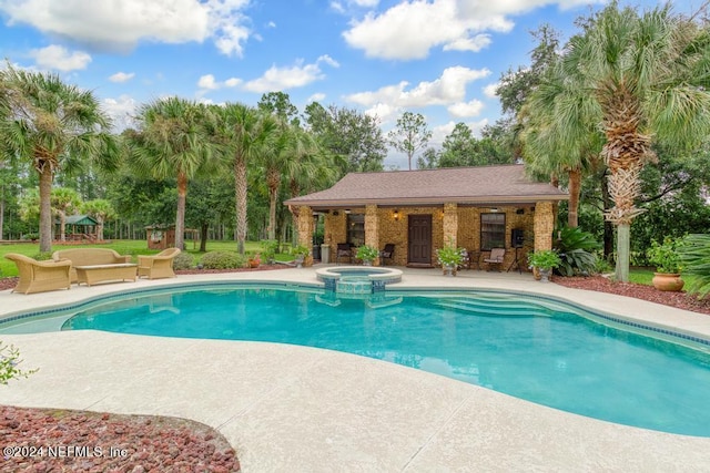 view of swimming pool featuring an outdoor structure, a pool with connected hot tub, and a patio area