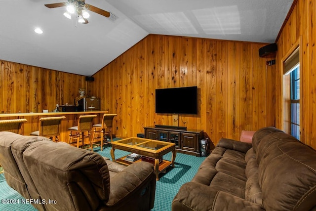carpeted living area with lofted ceiling, wooden walls, and ceiling fan