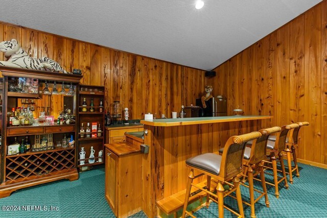 bar featuring freestanding refrigerator, wooden walls, bar area, a textured ceiling, and carpet