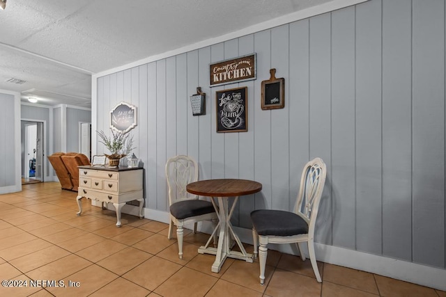 tiled dining room featuring wood walls and a textured ceiling