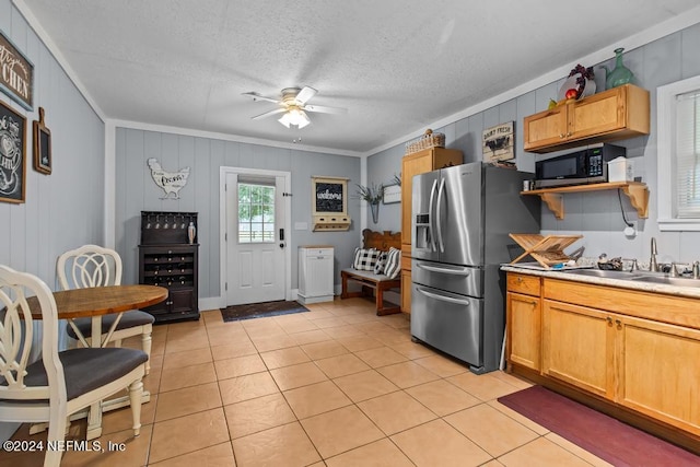kitchen with a sink, a ceiling fan, a textured ceiling, light tile patterned floors, and stainless steel appliances