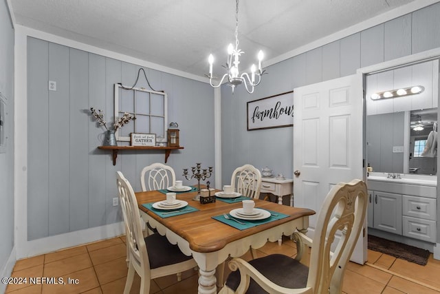 tiled dining space featuring ornamental molding and a chandelier