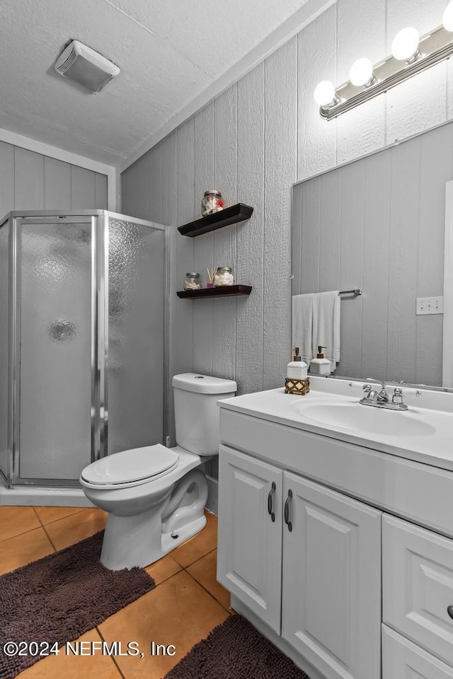 bathroom featuring toilet, walk in shower, wooden walls, tile patterned floors, and vanity