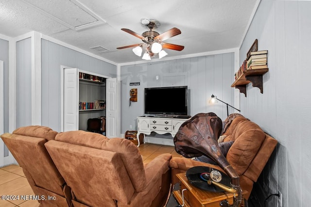 living area with tile patterned floors, visible vents, crown molding, and a ceiling fan