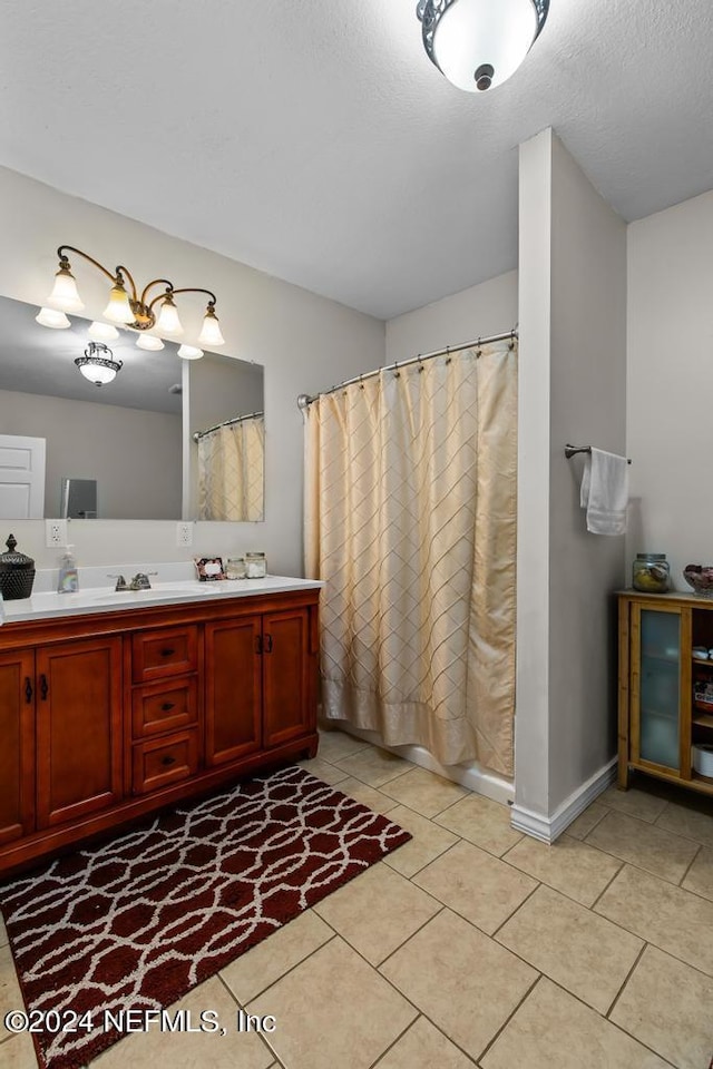 bathroom with a textured ceiling, vanity, tile patterned floors, and walk in shower