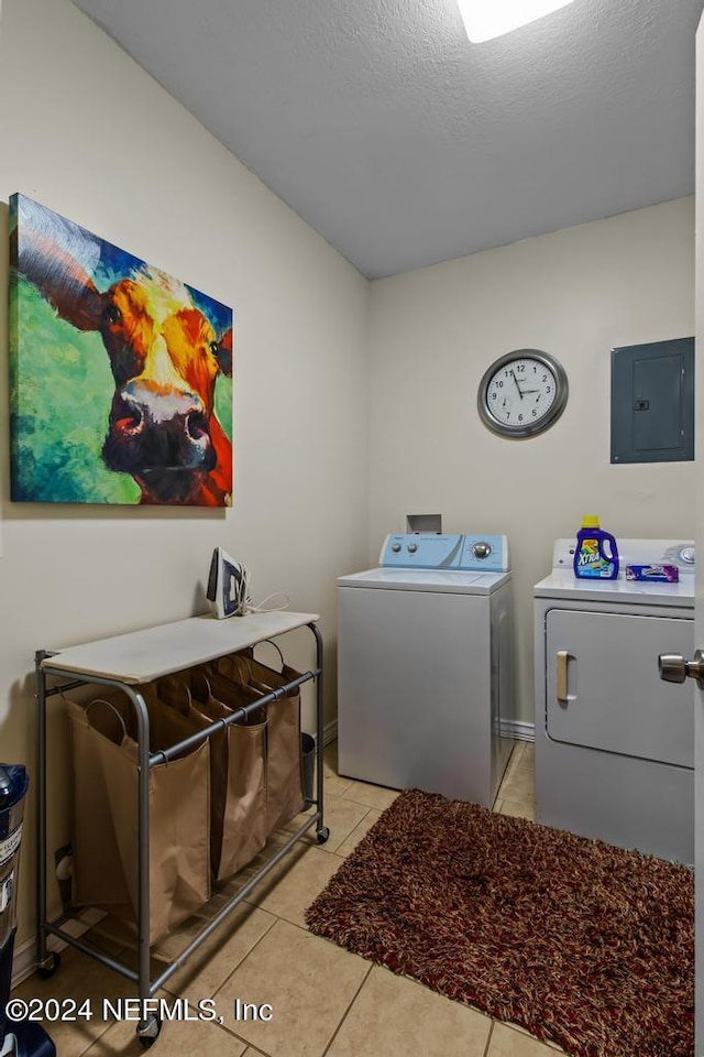 clothes washing area with electric panel, washer and clothes dryer, light tile patterned flooring, a textured ceiling, and laundry area