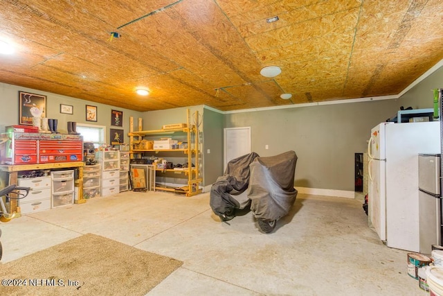 basement with freestanding refrigerator, ornamental molding, and baseboards