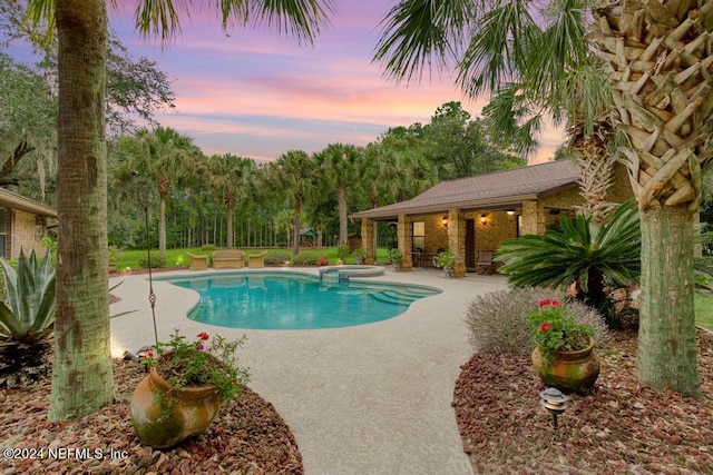 pool at dusk featuring a patio