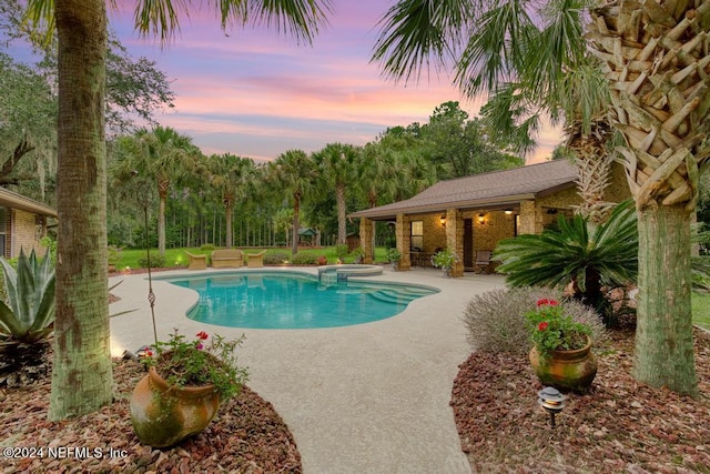 view of swimming pool featuring a pool with connected hot tub, an outbuilding, and a patio area