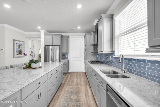 kitchen with gray cabinetry, sink, light stone counters, and stainless steel appliances