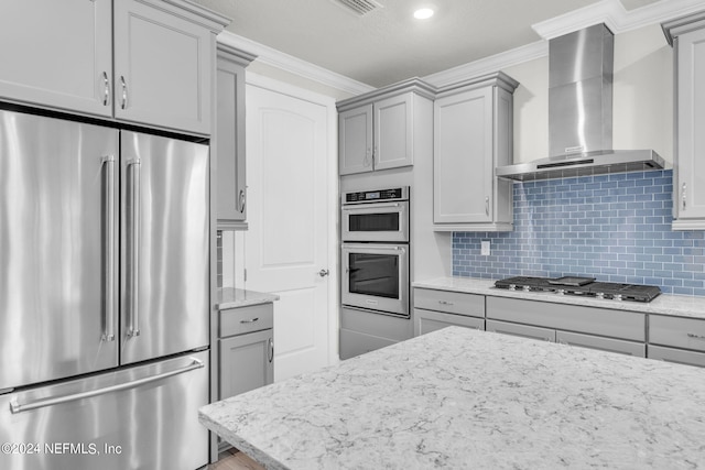 kitchen featuring tasteful backsplash, crown molding, wall chimney exhaust hood, and appliances with stainless steel finishes