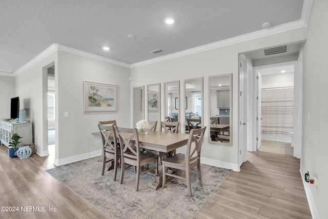 dining room featuring crown molding, light hardwood / wood-style floors, and a textured ceiling