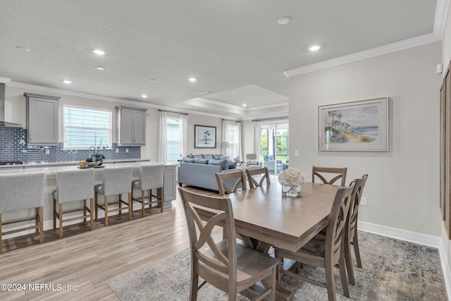 dining area with crown molding, plenty of natural light, a textured ceiling, and light hardwood / wood-style floors